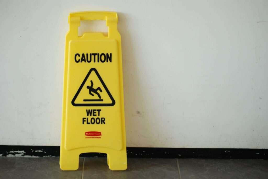a wet floor caution sign against a white wall