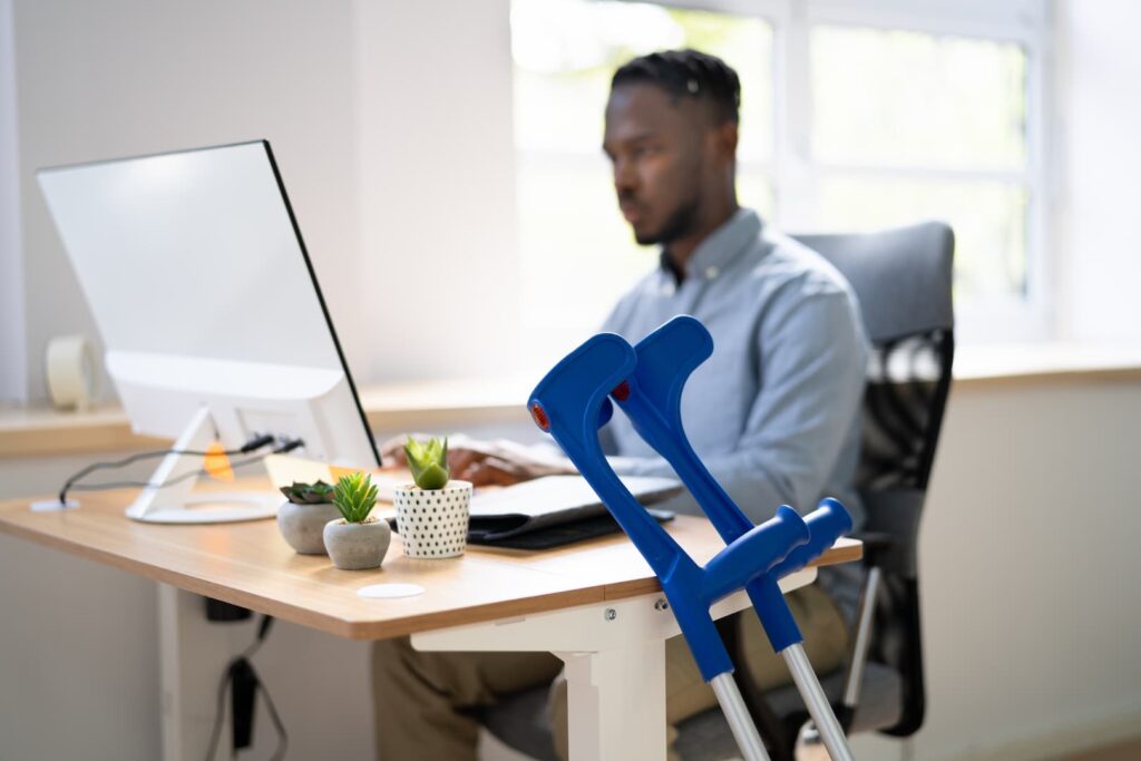 a person sitting at a desk with crutches