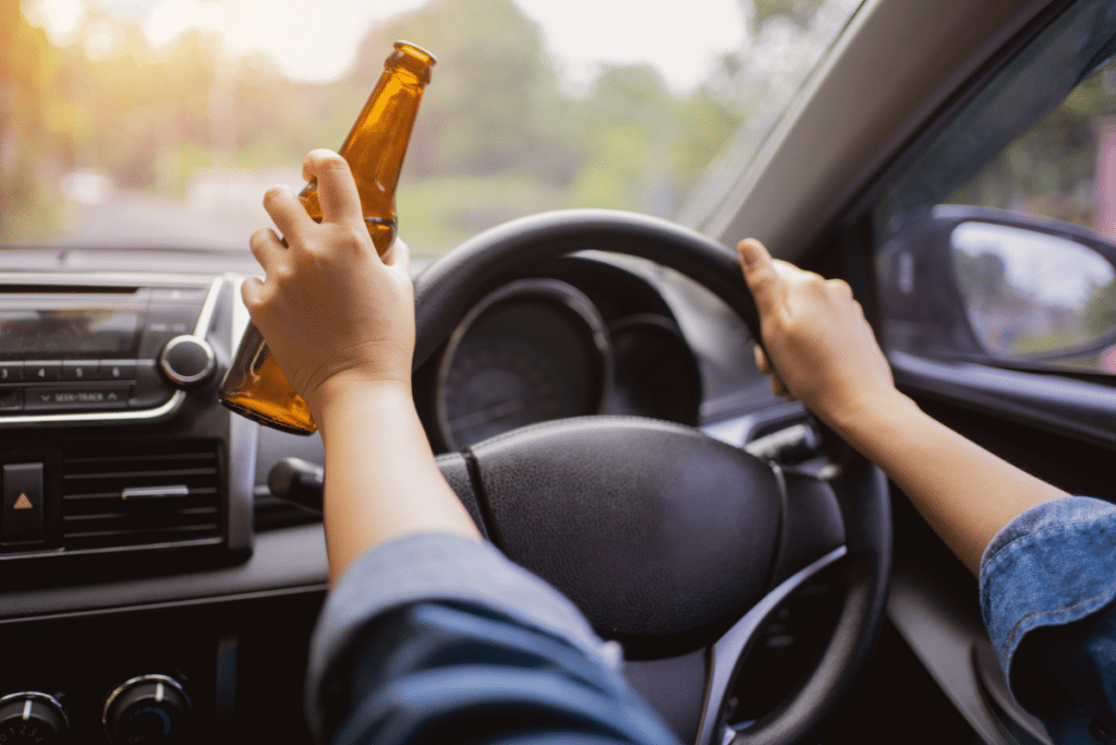 a person holding a bottle of beer while driving