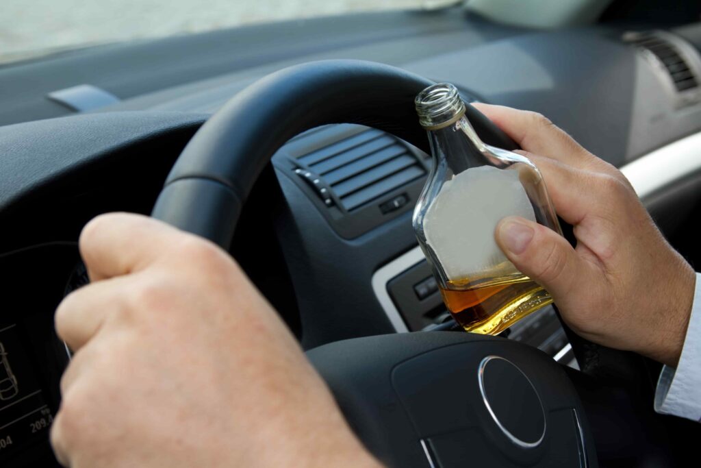 a person holding a bottle of alcohol while driving