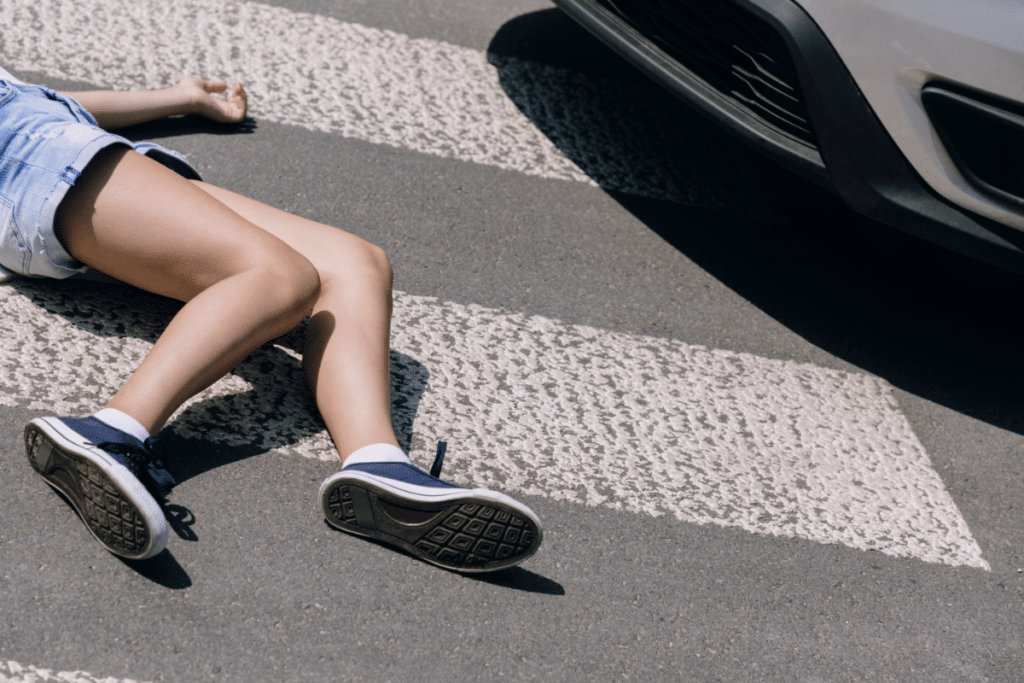 a person lying on pedestrian next to a car