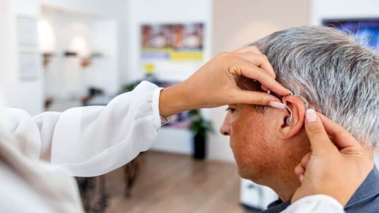 a person adjusting a hearing aid