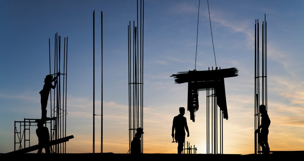 Silhouette workers on high building site with sunset sky background