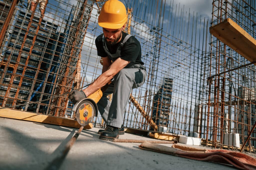 man using grinding machine to cut metal pieces in construction site