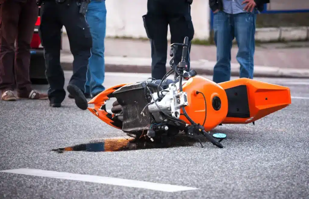 Orange motorcycle laying on the asphalt after being involved in an accident