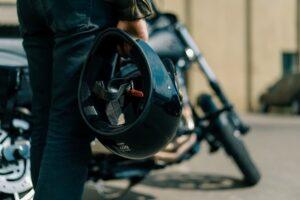 brutal biker standing near a black motorcycle before the start of the race holding a helmet in his hands lust for speed