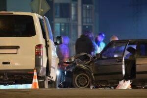 Cars crashed heavily in road accident after collision and silhouette of people on city street at night. Road safety and insurance concept