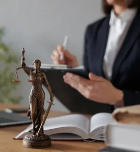 Mujer trabajando en escritorio con estatua de balanza de justicia y libros sobre la mesa