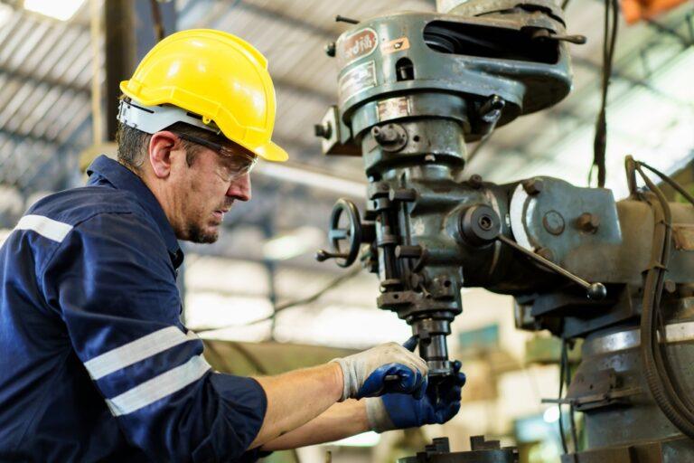 Professional caucasian white ethnicity male technician operating the heavy duty machine in the lathing factory.