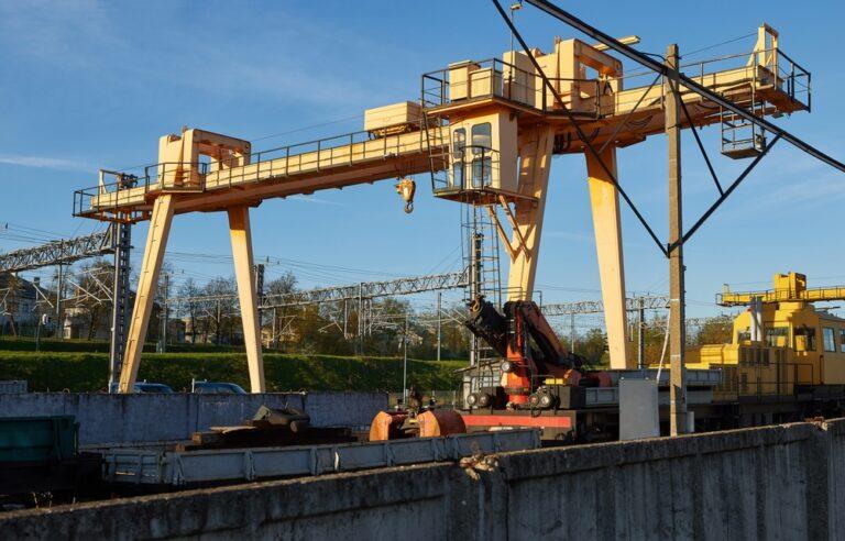 A steel gantry crane moves heavy equipment at an industrial work site where a crane or hoist has the potential to cause injuries.