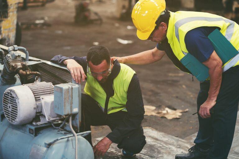 A worker sits on the ground after an equipment accident as a coworker checks on him, and the worker wonders what to do if they’re hurt using defective work equipment. 