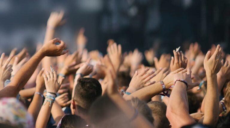 A crowd of people cheering at a concert. Find out what to do if you are injured at a concert or event venue.