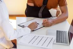 A man with his arm in a sling talking to a doctor. Find out what to do if your car accident symptoms start days later.
