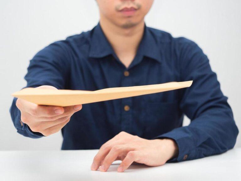 A businessman handing someone an envelope. Find out what to do if your employer offers you cash instead of reporting your injury.