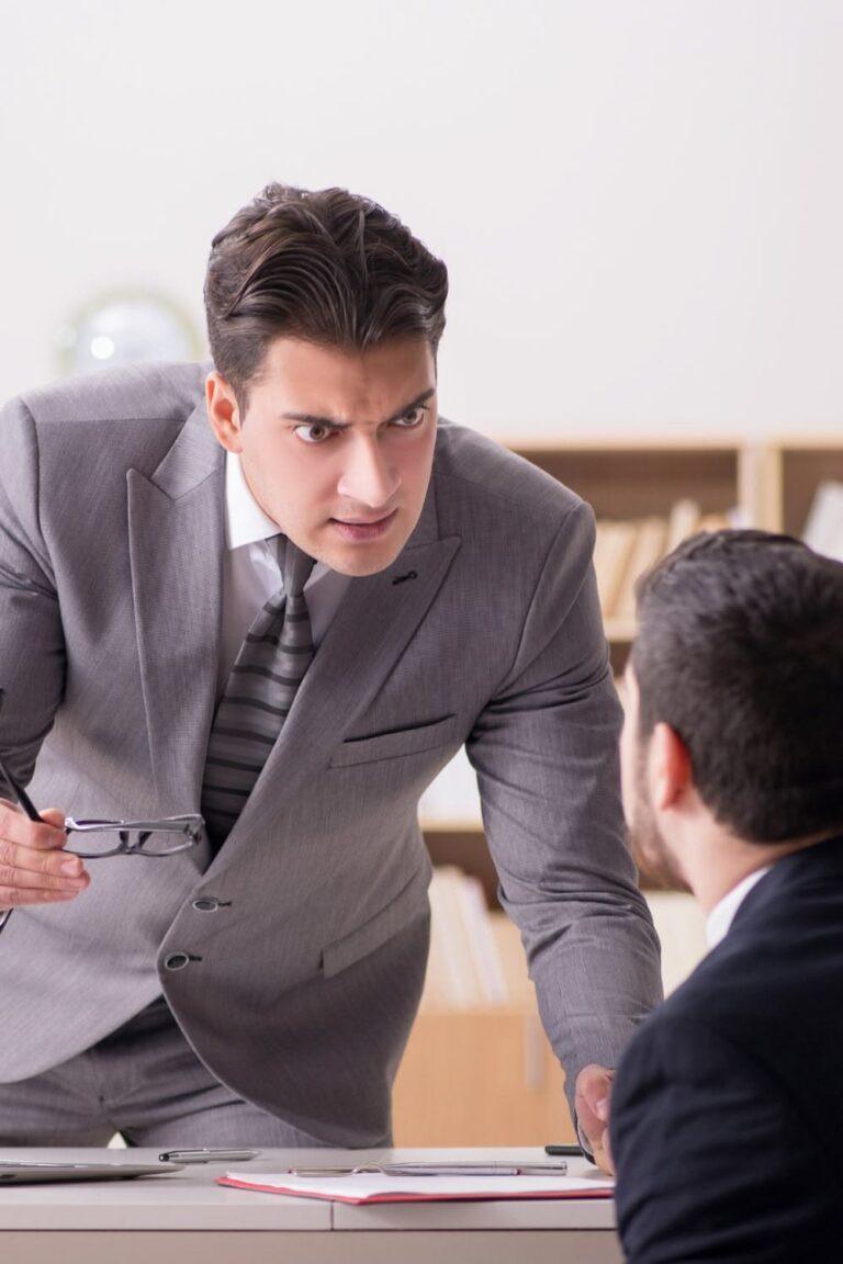 A businessman staring angrily at another businessman. Find out what happens if your employer says you violated a safety rule before your injury.