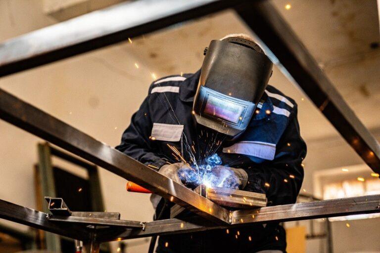 A welder performs metal fabrication work in an industrial setting where workers may be exposed to hazardous welding fumes.